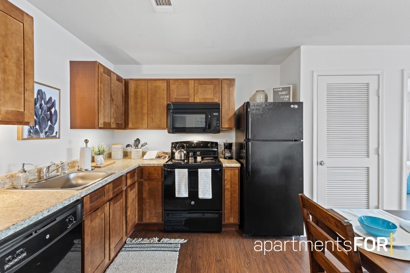 a kitchen with a black refrigerator and wooden cabinets
