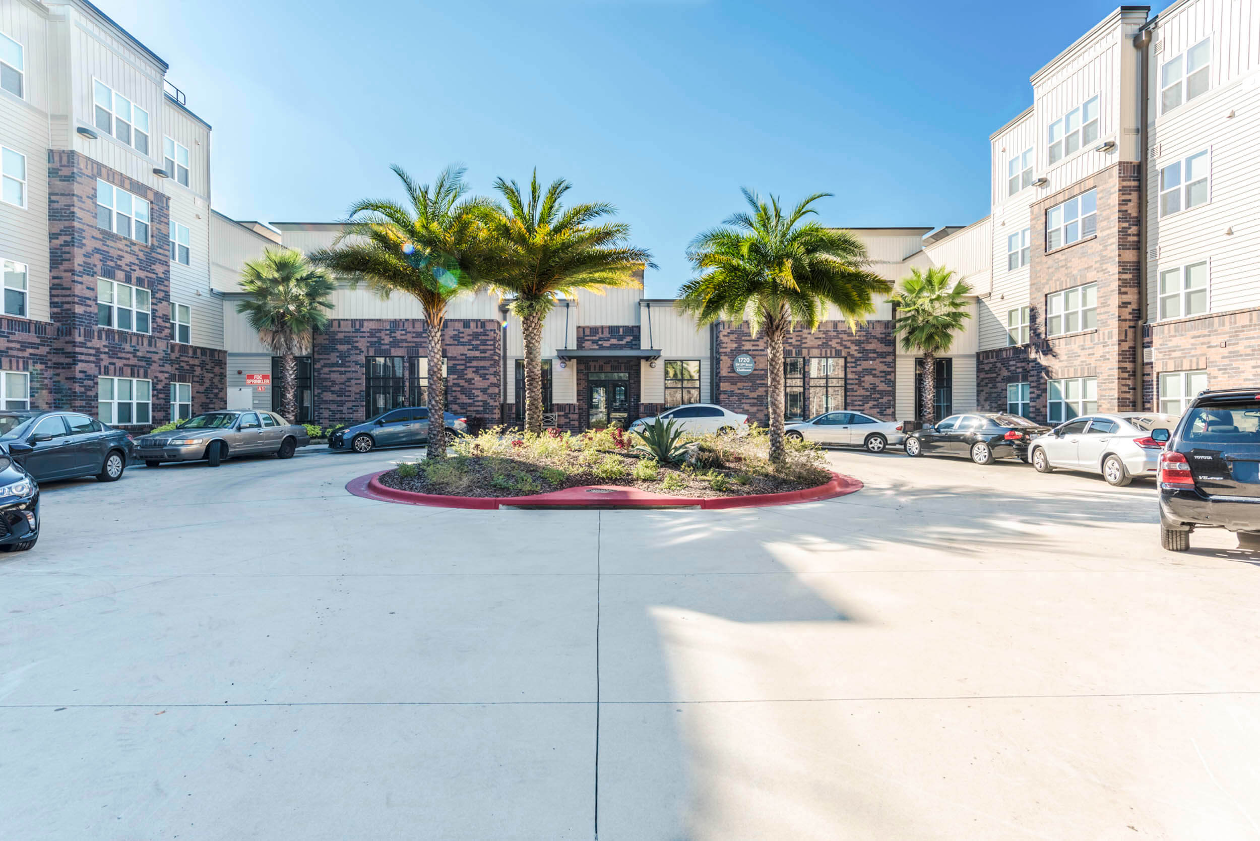 a building with palm trees and cars in front of it